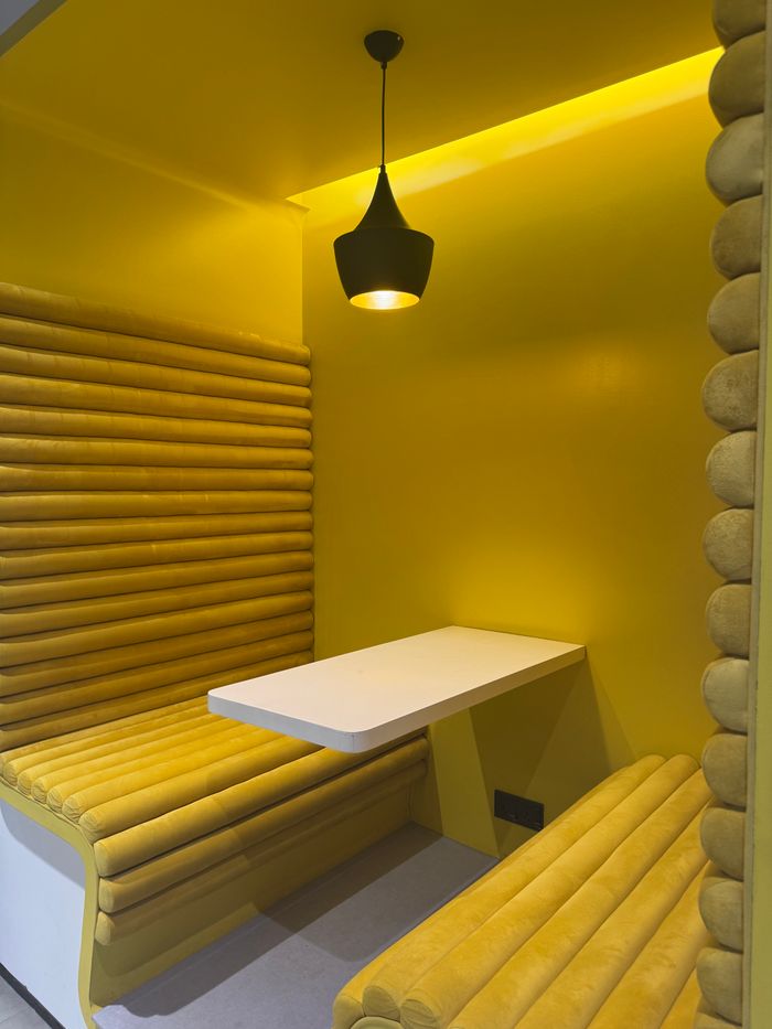 A stylish yellow seating booth with a pendant light in a Dhaka cafe, perfect for modern interiors.